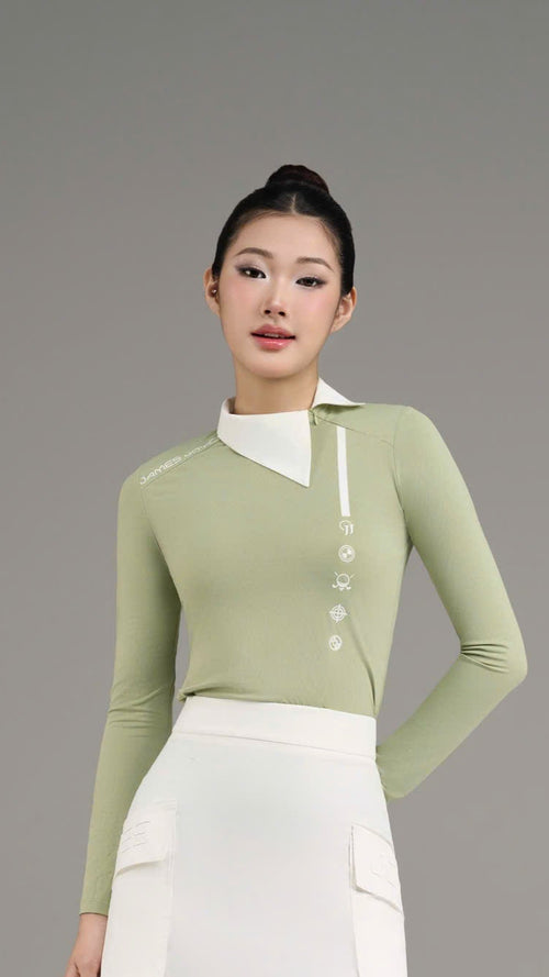 Woman wearing a green top and white skirt with knee-high socks and shoes on a gray background